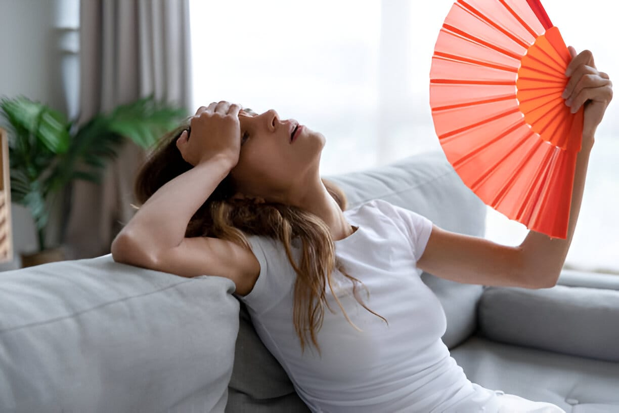Woman with a hand fan suffering from high temperatures