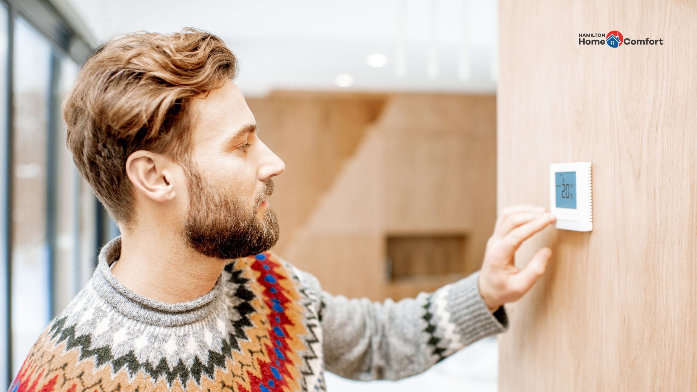 Man adjusting thermostat - Fall furnace maintenance checklist tips from Hamilton Home Comfort.
