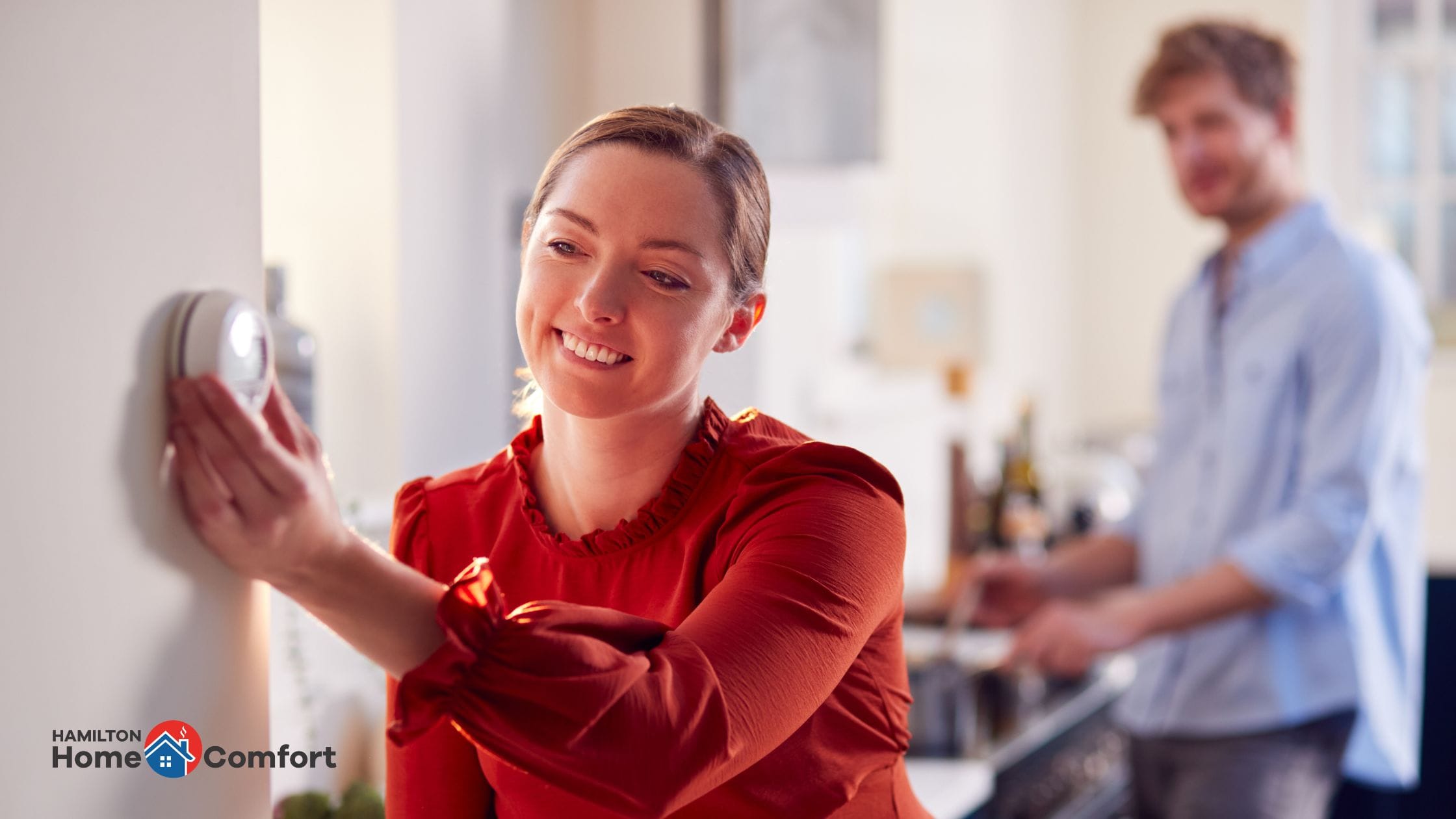 Woman adjusting a furnace thermostat - your guide to your furnace in Hamilton with Hamilton Home Comfort.